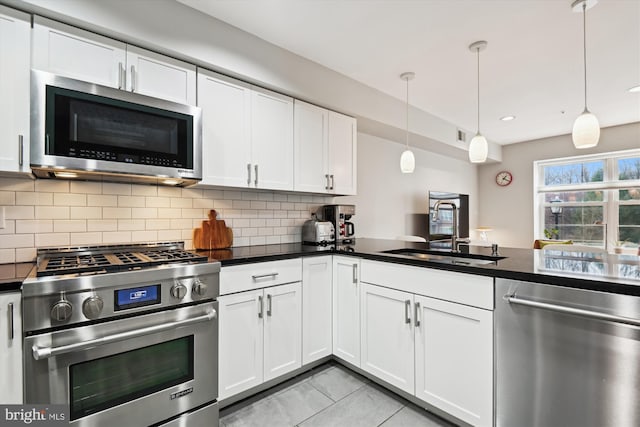 kitchen with white cabinetry, stainless steel appliances, decorative light fixtures, and sink