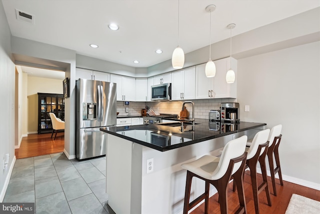 kitchen featuring white cabinetry, sink, a breakfast bar area, kitchen peninsula, and stainless steel appliances