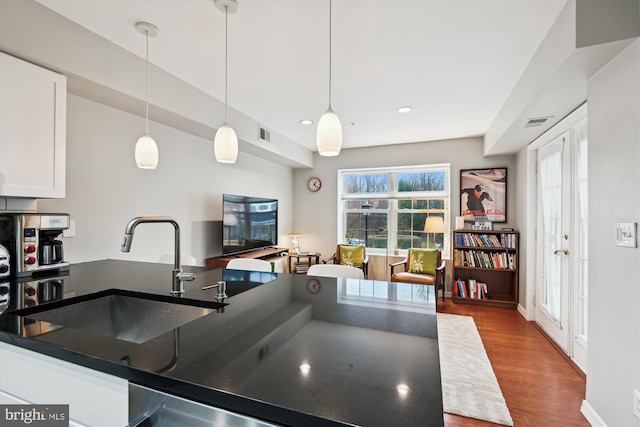 kitchen featuring white cabinetry, sink, decorative light fixtures, and wood-type flooring