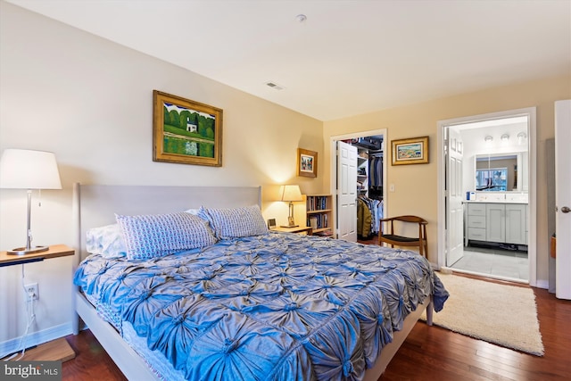 bedroom with hardwood / wood-style floors, a spacious closet, ensuite bath, and a closet