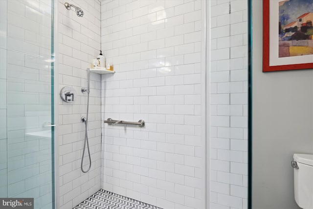 bathroom with a tile shower and toilet