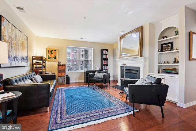 living room featuring wood-type flooring and built in features