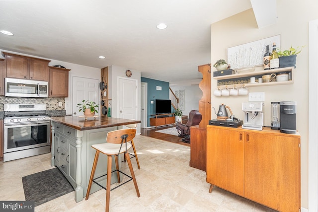 kitchen featuring tasteful backsplash, stainless steel appliances, a center island, and a kitchen bar