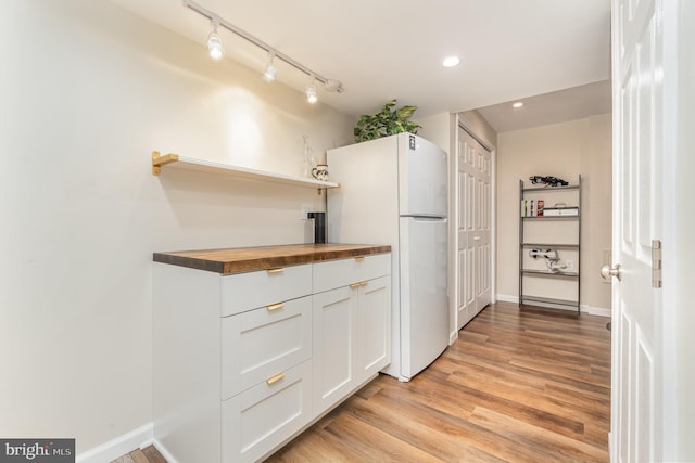 kitchen featuring white cabinetry, light hardwood / wood-style floors, butcher block countertops, and white fridge