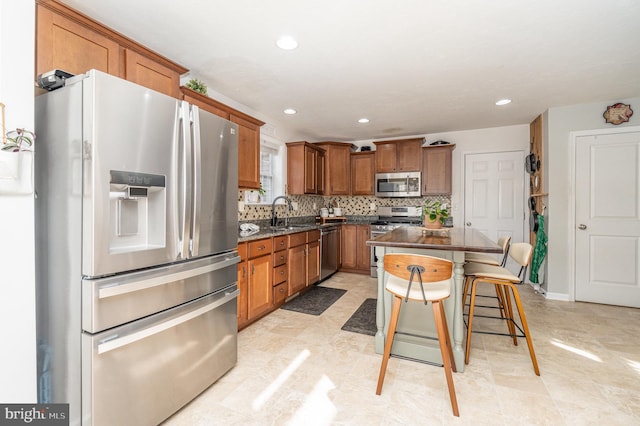 kitchen featuring sink, stainless steel appliances, a center island, a kitchen bar, and decorative backsplash