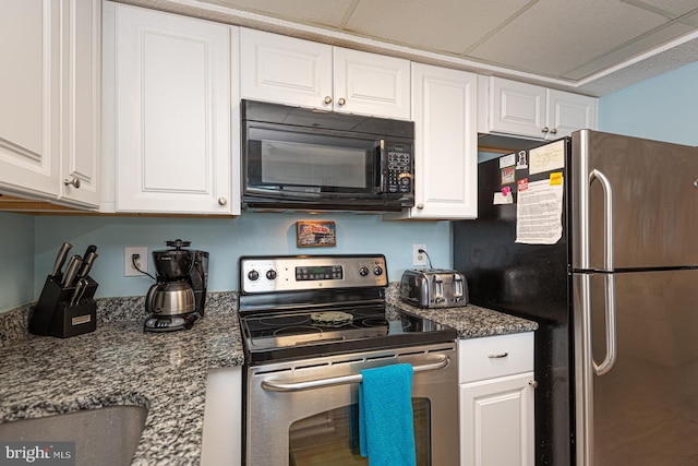 kitchen with appliances with stainless steel finishes, dark stone counters, and white cabinets