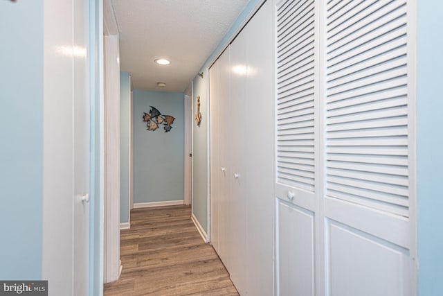 corridor featuring light hardwood / wood-style flooring and a textured ceiling