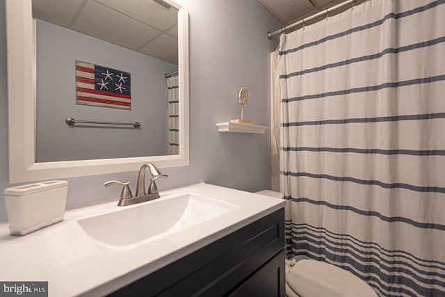 bathroom with vanity, toilet, and a drop ceiling