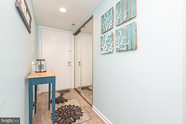 corridor with hardwood / wood-style floors and a textured ceiling