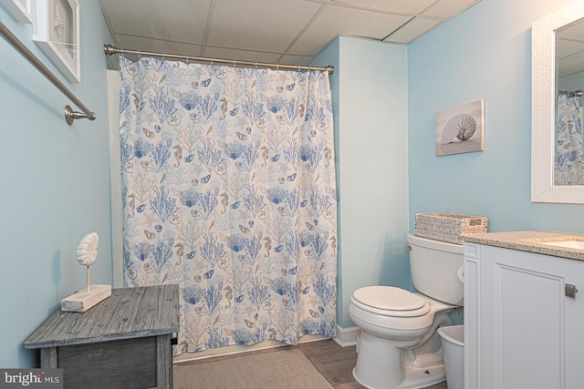 bathroom featuring hardwood / wood-style flooring, vanity, a drop ceiling, curtained shower, and toilet