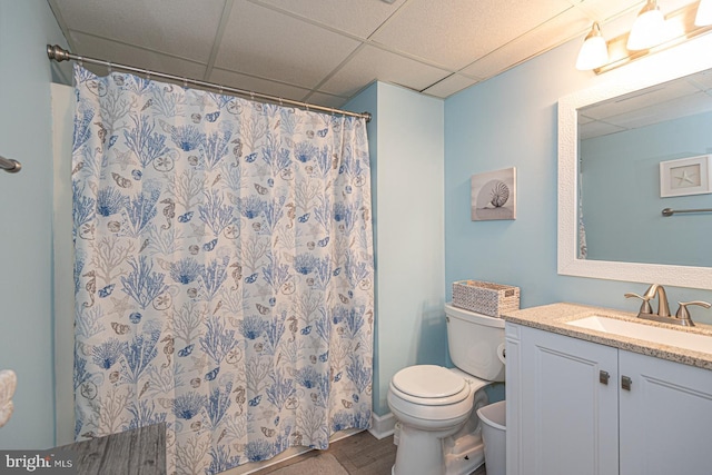 bathroom featuring vanity, toilet, a shower with shower curtain, and a drop ceiling