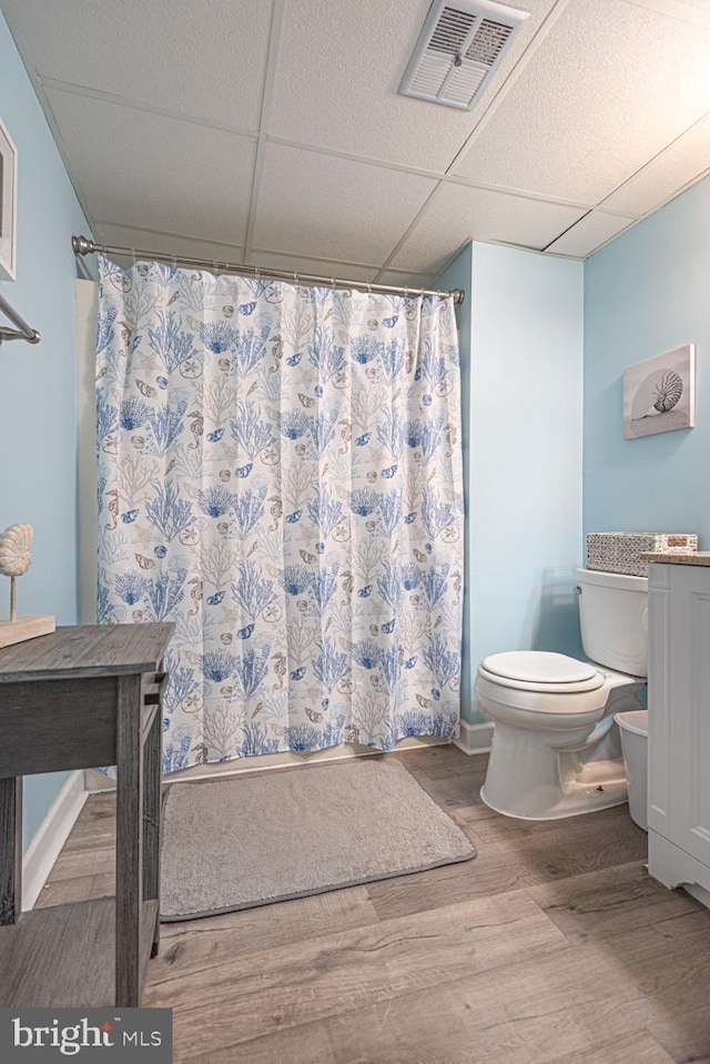 bathroom featuring hardwood / wood-style flooring, vanity, a paneled ceiling, and toilet