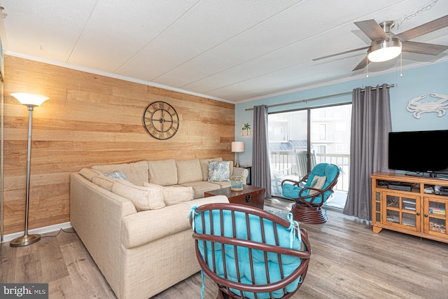 living room with hardwood / wood-style flooring, ornamental molding, and wooden walls