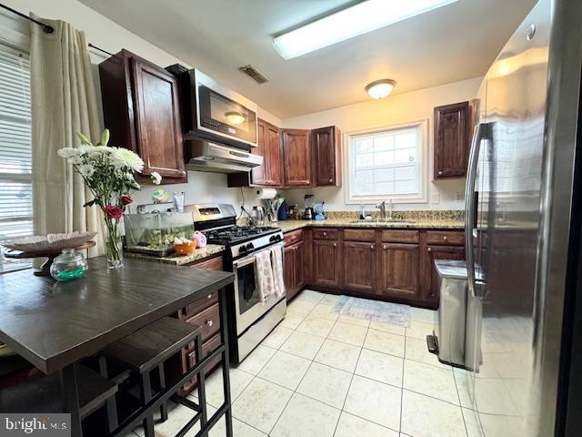 kitchen with light tile patterned flooring, appliances with stainless steel finishes, and sink