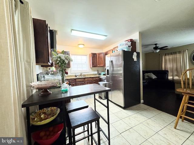 kitchen featuring light tile patterned flooring, stainless steel fridge, and ceiling fan