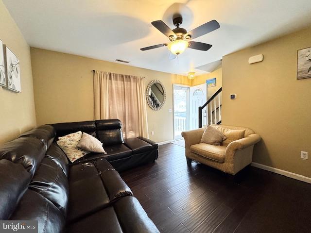 living room featuring dark wood-type flooring and ceiling fan