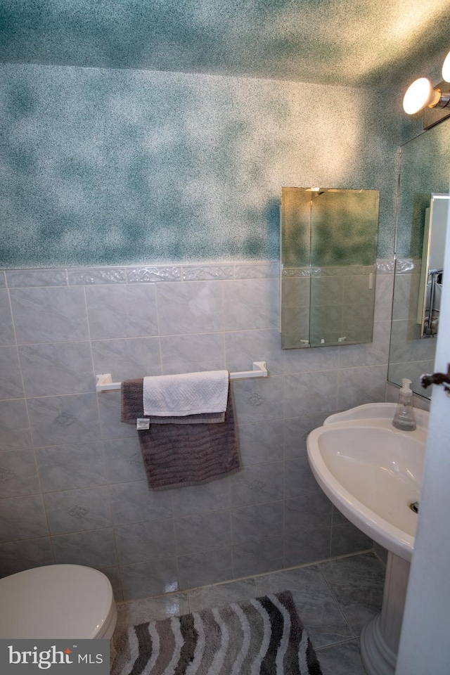 bathroom with tile walls and toilet