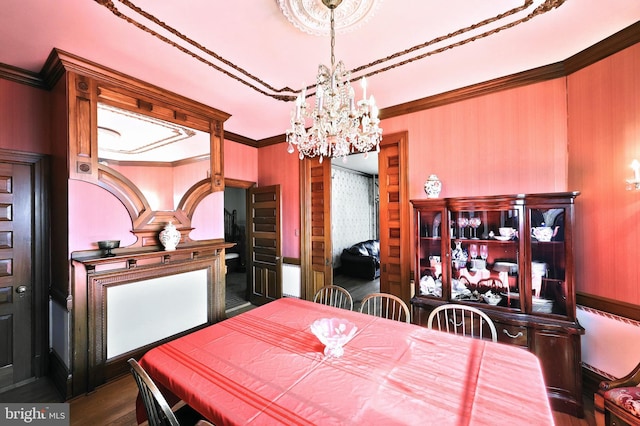 dining room with ornamental molding, an inviting chandelier, and wood-type flooring