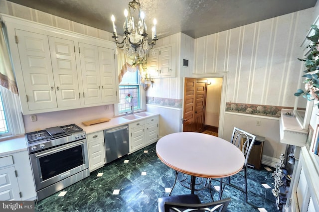 kitchen with sink, a notable chandelier, stainless steel appliances, white cabinets, and hanging light fixtures