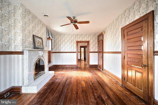 unfurnished living room featuring a tile fireplace, ceiling fan, and dark hardwood / wood-style flooring