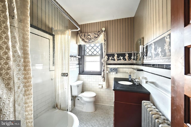 bathroom featuring tile patterned floors, radiator, toilet, tile walls, and vanity