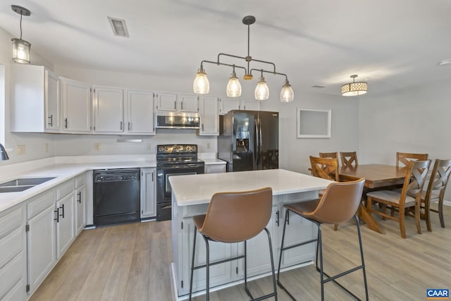 kitchen with white cabinetry, sink, black appliances, and hanging light fixtures