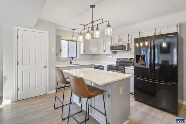 kitchen with a kitchen island, sink, white cabinets, hanging light fixtures, and black appliances