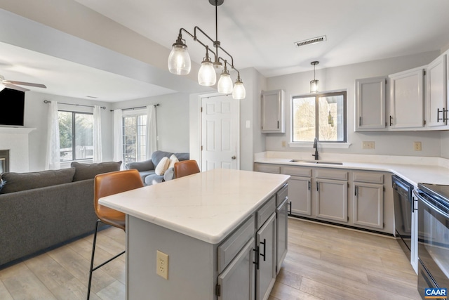 kitchen with a kitchen island, decorative light fixtures, sink, gray cabinetry, and a kitchen bar