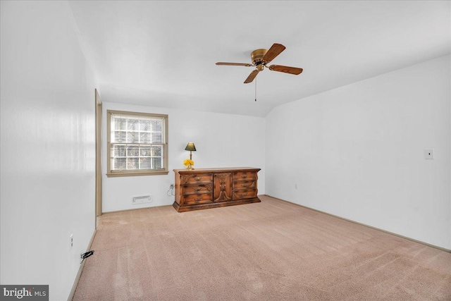 spare room featuring ceiling fan, vaulted ceiling, and light carpet