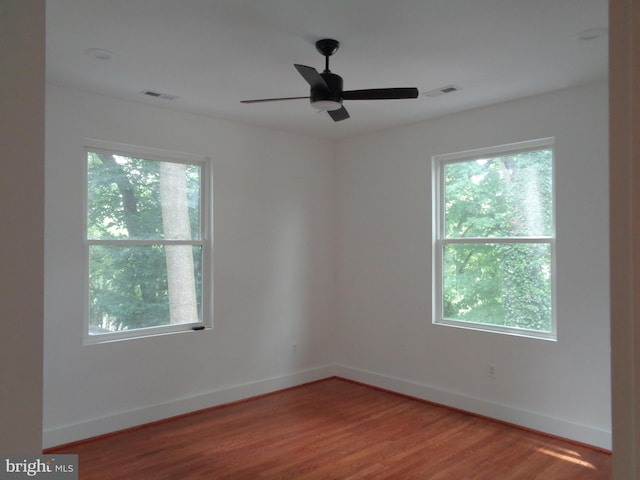 spare room featuring hardwood / wood-style flooring, ceiling fan, and plenty of natural light