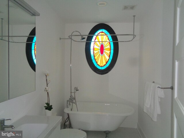 bathroom with toilet, sink, and a tub to relax in