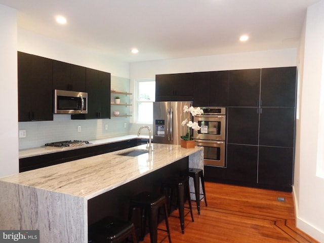 kitchen with stainless steel appliances, a kitchen island with sink, sink, and a kitchen breakfast bar