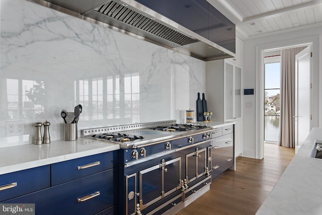 kitchen featuring hardwood / wood-style floors, beam ceiling, backsplash, blue cabinets, and wall chimney exhaust hood