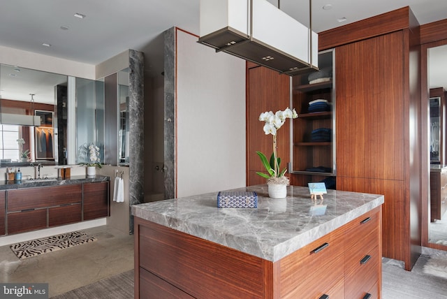 interior space with sink, light stone countertops, and a kitchen island