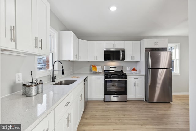 kitchen with appliances with stainless steel finishes, white cabinetry, and a sink