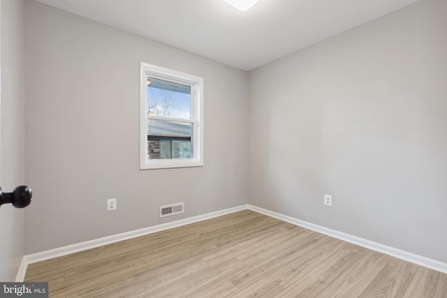 empty room with light wood-style floors, baseboards, and visible vents