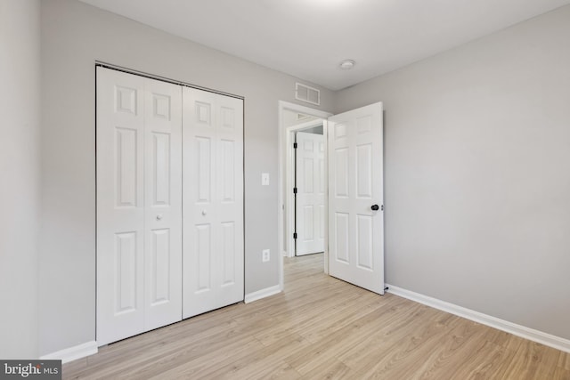 unfurnished bedroom with light wood finished floors, baseboards, visible vents, and a closet