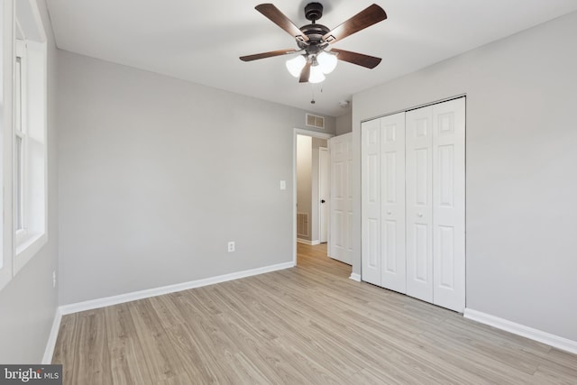 unfurnished bedroom featuring a ceiling fan, baseboards, visible vents, light wood-style floors, and a closet