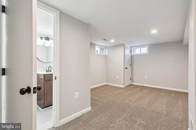 below grade area featuring light carpet, recessed lighting, visible vents, and baseboards