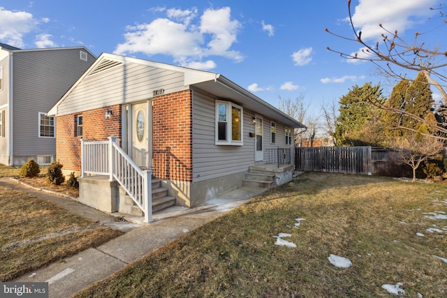 view of home's exterior featuring brick siding, fence, and a lawn