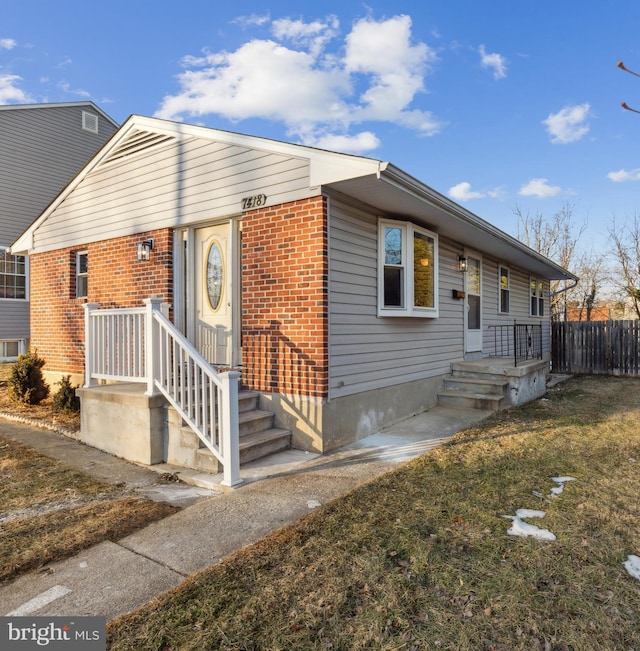 view of front of home featuring fence, a front lawn, and brick siding