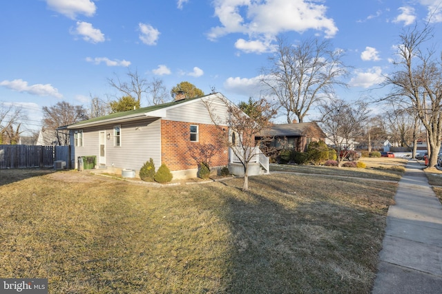 view of property exterior with central AC unit, a chimney, fence, a yard, and brick siding