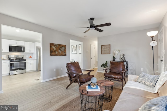 living room featuring a ceiling fan, light wood-type flooring, and baseboards