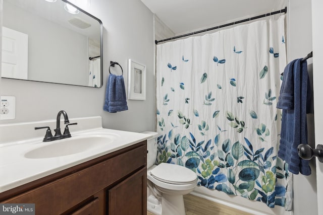 bathroom with toilet, shower / bath combo with shower curtain, and vanity