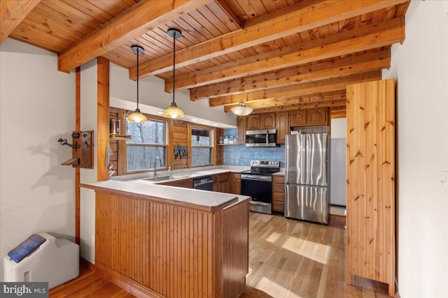 kitchen with pendant lighting, sink, stainless steel appliances, tasteful backsplash, and kitchen peninsula