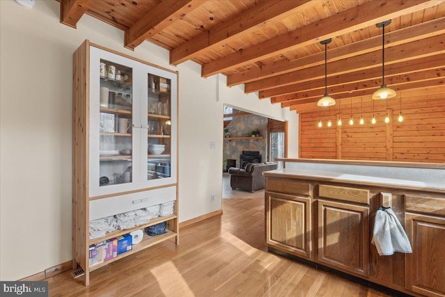 kitchen with a large fireplace, pendant lighting, wooden ceiling, and light hardwood / wood-style floors