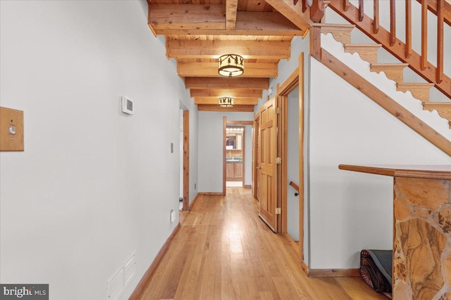 hall with beamed ceiling and light wood-type flooring