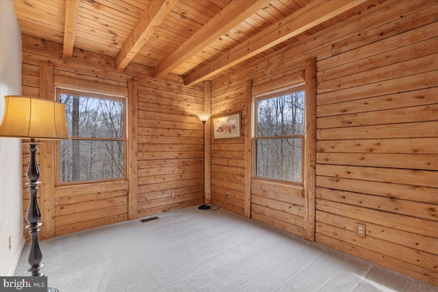 unfurnished room featuring wood ceiling, a healthy amount of sunlight, beam ceiling, and carpet