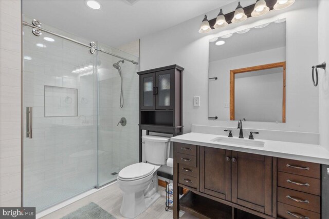 bathroom with an enclosed shower, vanity, and toilet