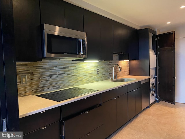 kitchen featuring stacked washer and clothes dryer, sink, black electric stovetop, and decorative backsplash